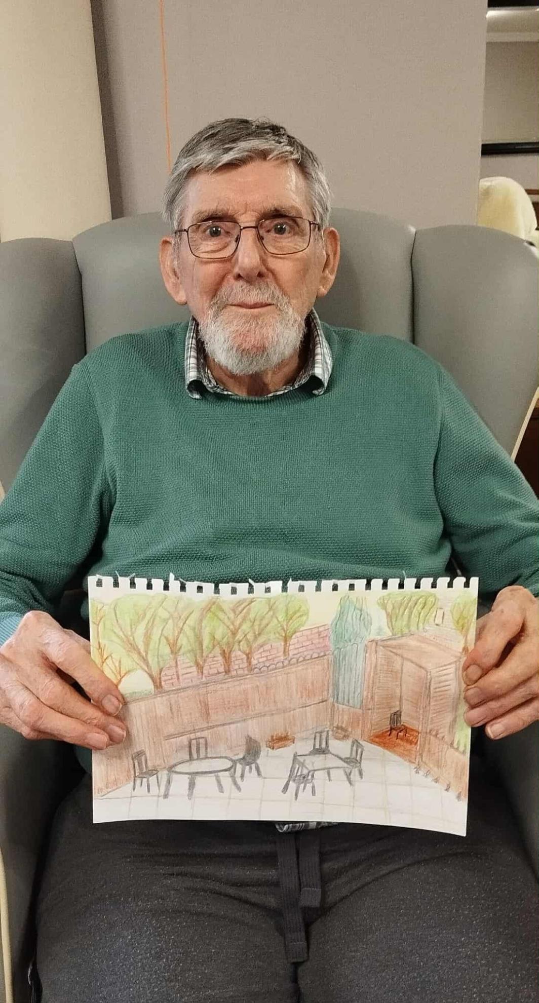 Photo of a man sitting in a chair and holding a drawing