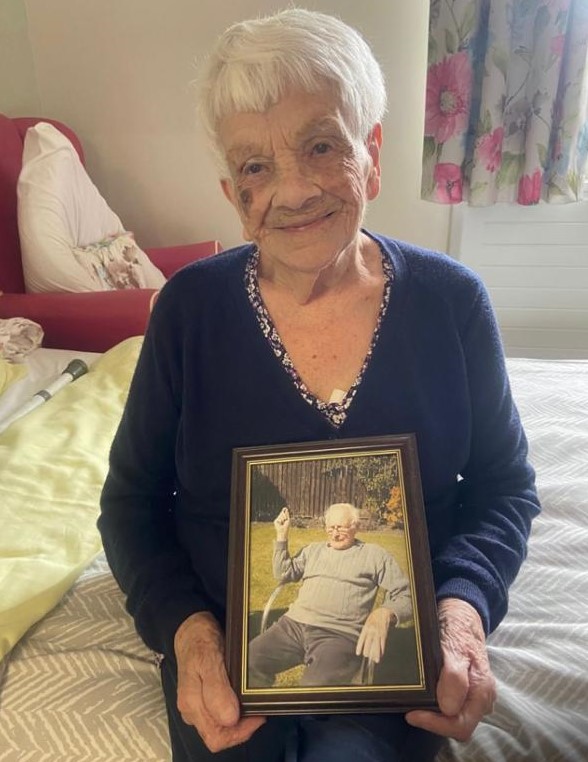 Photo of Norma holding framed photo of her late husband