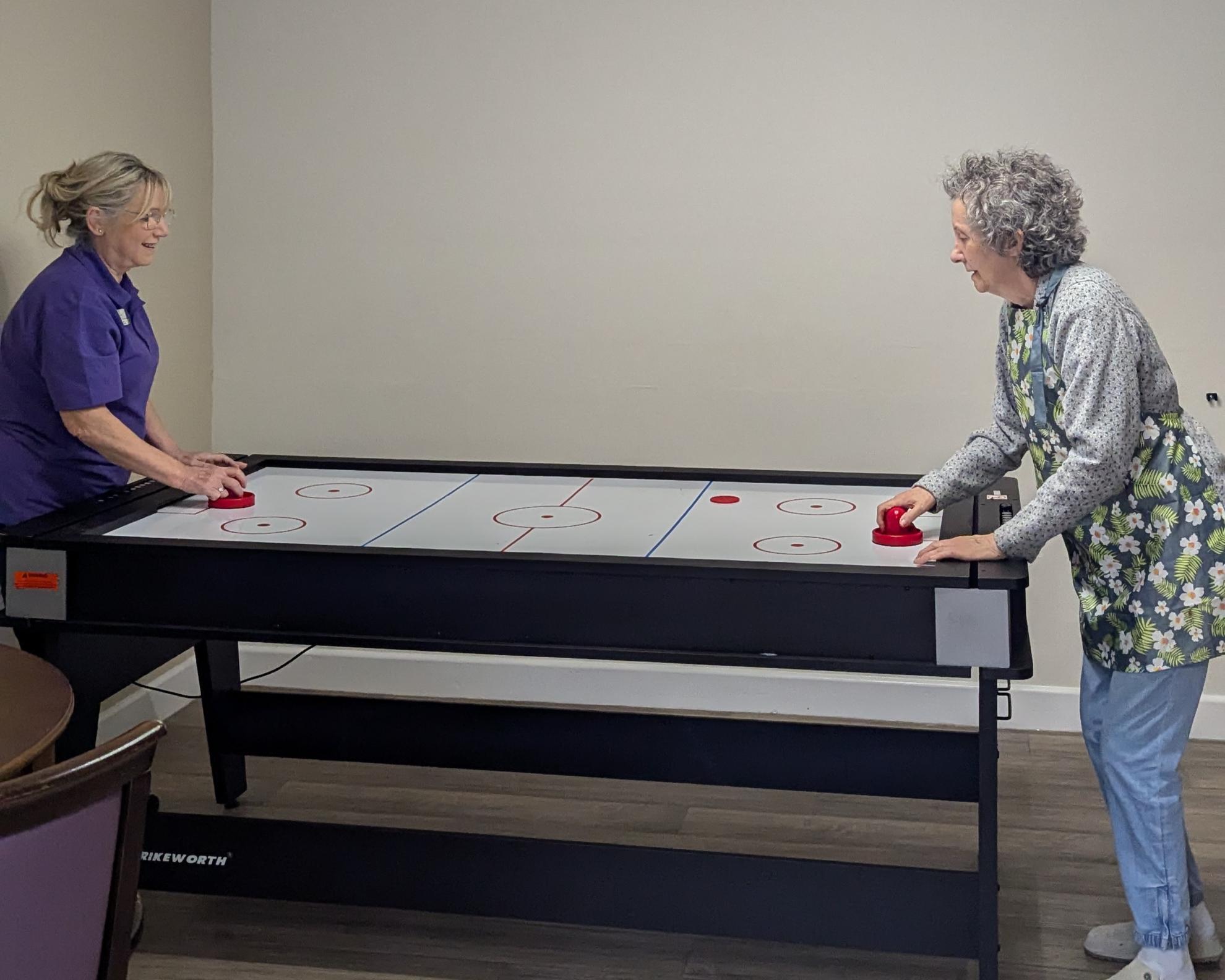 Susan playing air hockey with Dementia Support Worker 