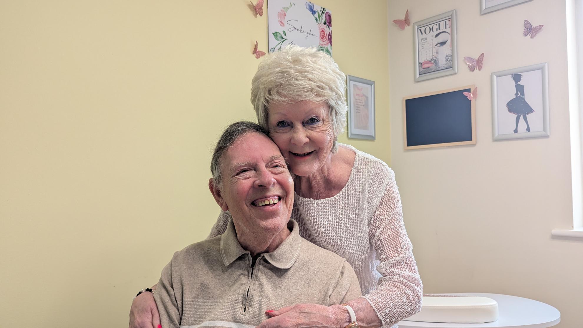 Albert and Collette smile and share loving hug