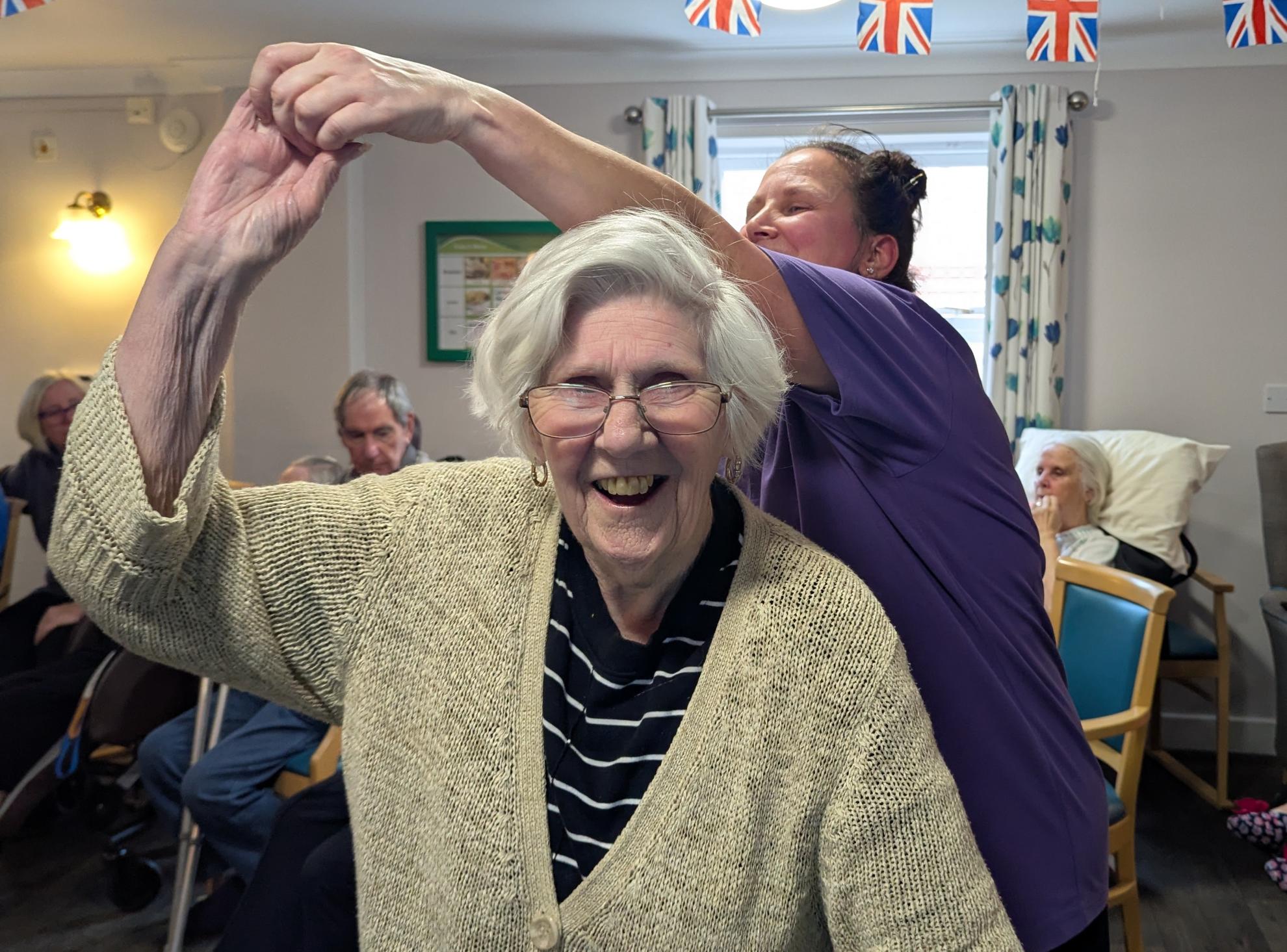 Photo of lady resident smiling and dancing with team member