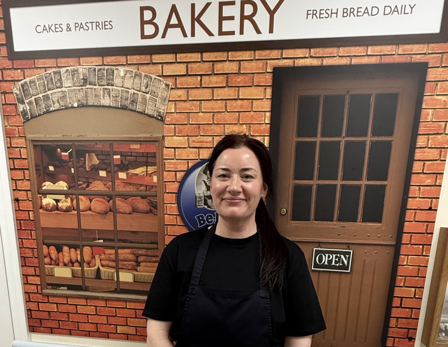 Stacy smiling in front of bakery backdrop