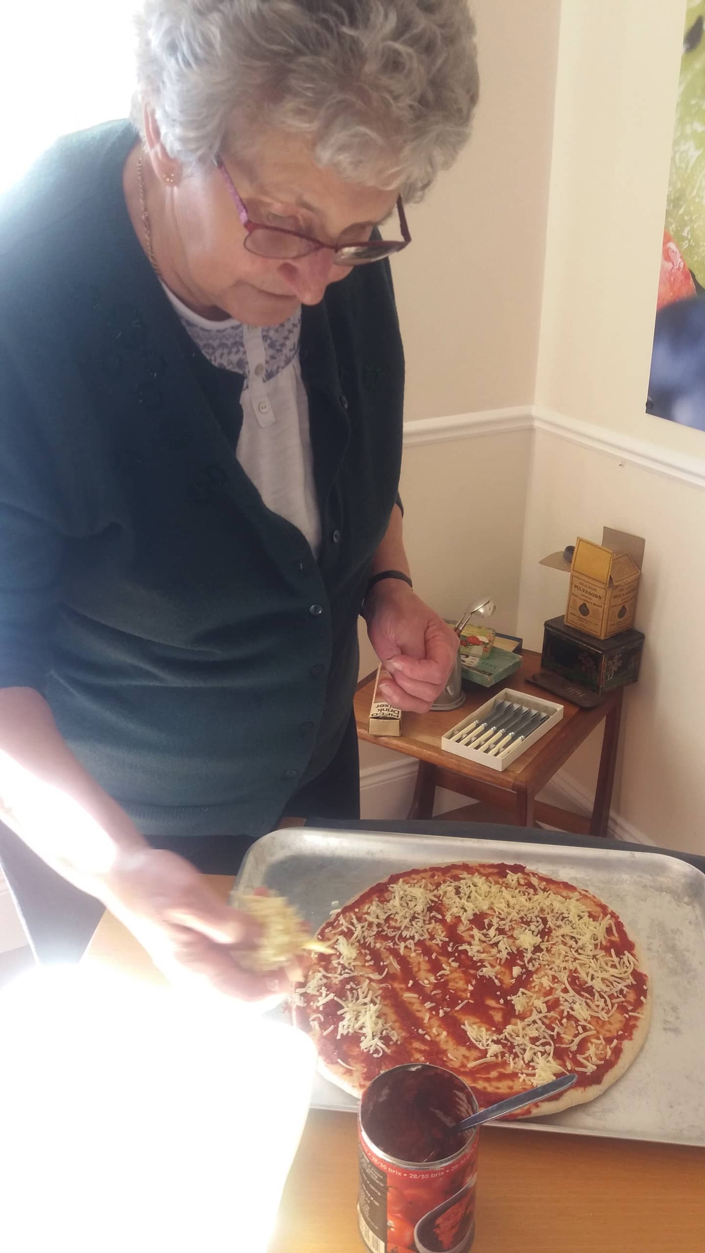 Resident carefully creating her pizza.