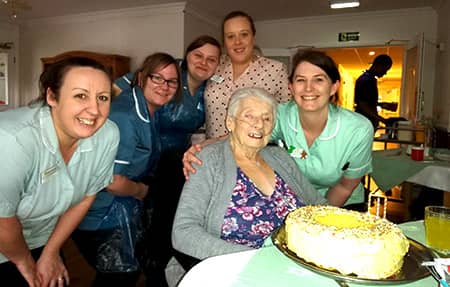 Mary enjoying her cake with staff on her 90th birthday.