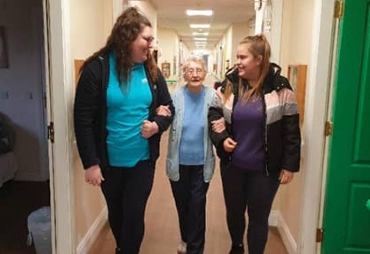 Residents walking with the homes Activity Coordinator and a visitor from the Girls Brigade.