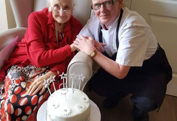 Cook giving resident the cake she made for her birthday