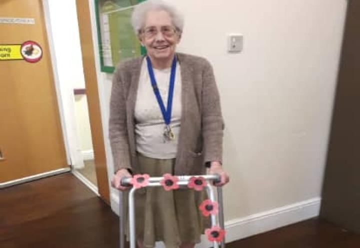 resident stood with her poppy decorated walking aid. 