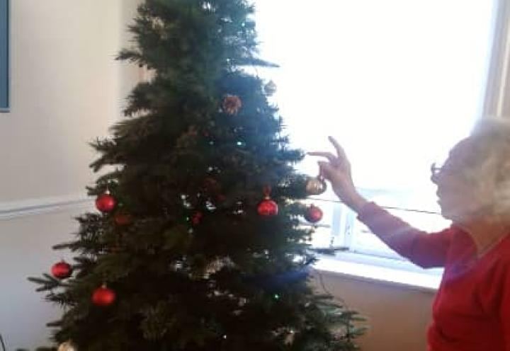 resident putting decorations on the Christmas tree. 