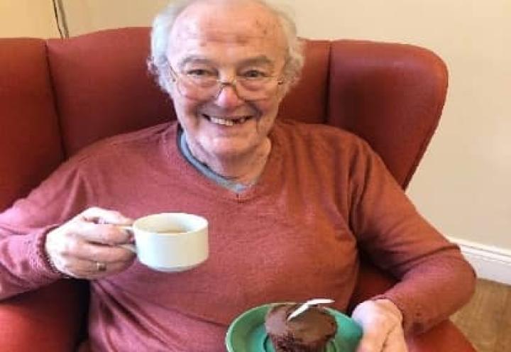resident with a cup of tea and cake slice. 