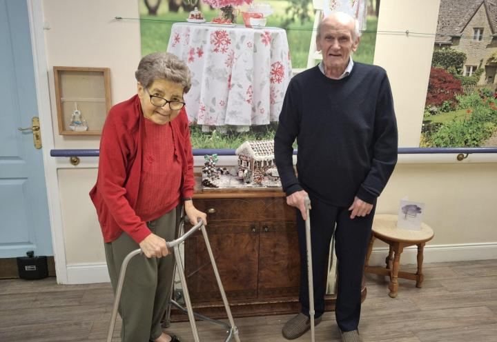 Photo of 2 people with a gingerbread house