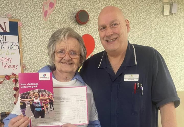photo of 2 people smiling, one person holds a sponsorship form