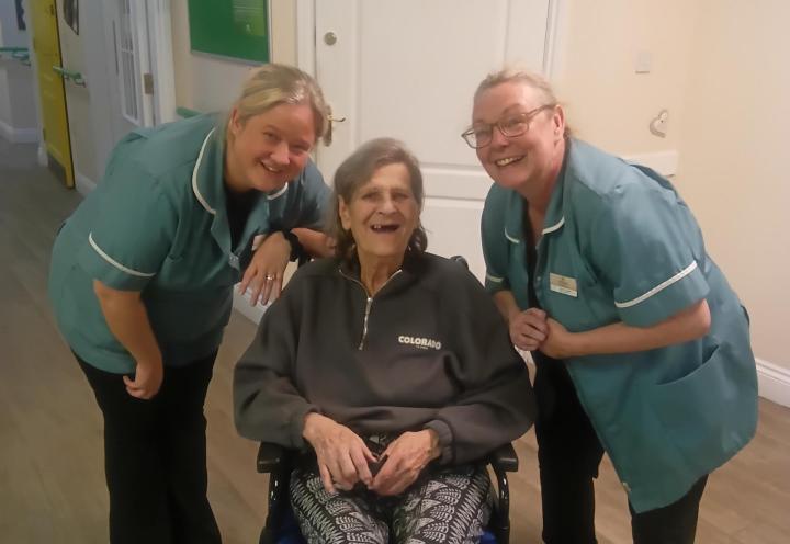 photo of 3 people smiling, one person sits in a wheelchair