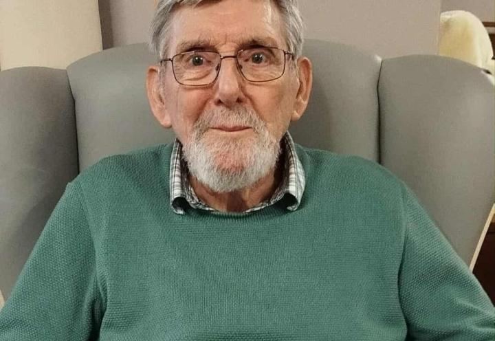 Photo of a person sat in a chair holding a drawing 