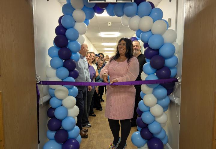 Photo of home manager cutting the ribbon to the new community